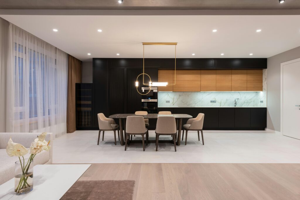 Spacious modern kitchen with elegant decor, featuring a dining area and contemporary lighting.